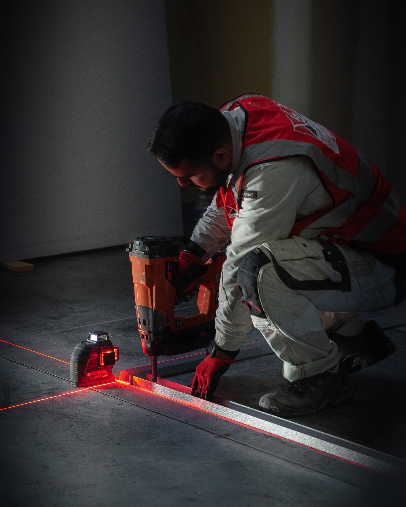 Un plaquiste ALP fixe une ossature au sol en suivant les rep&egrave;res d&rsquo;un niveau laser.